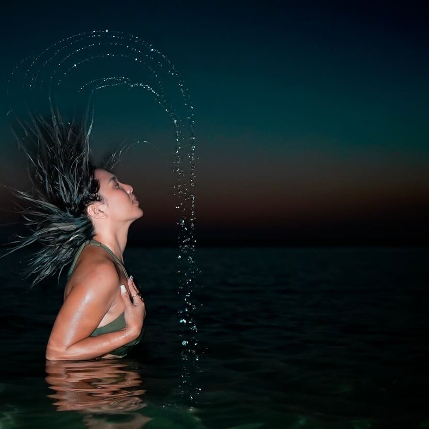Night photo of Lex Arianne in water with moon glowing behind – Dubai beach photography"